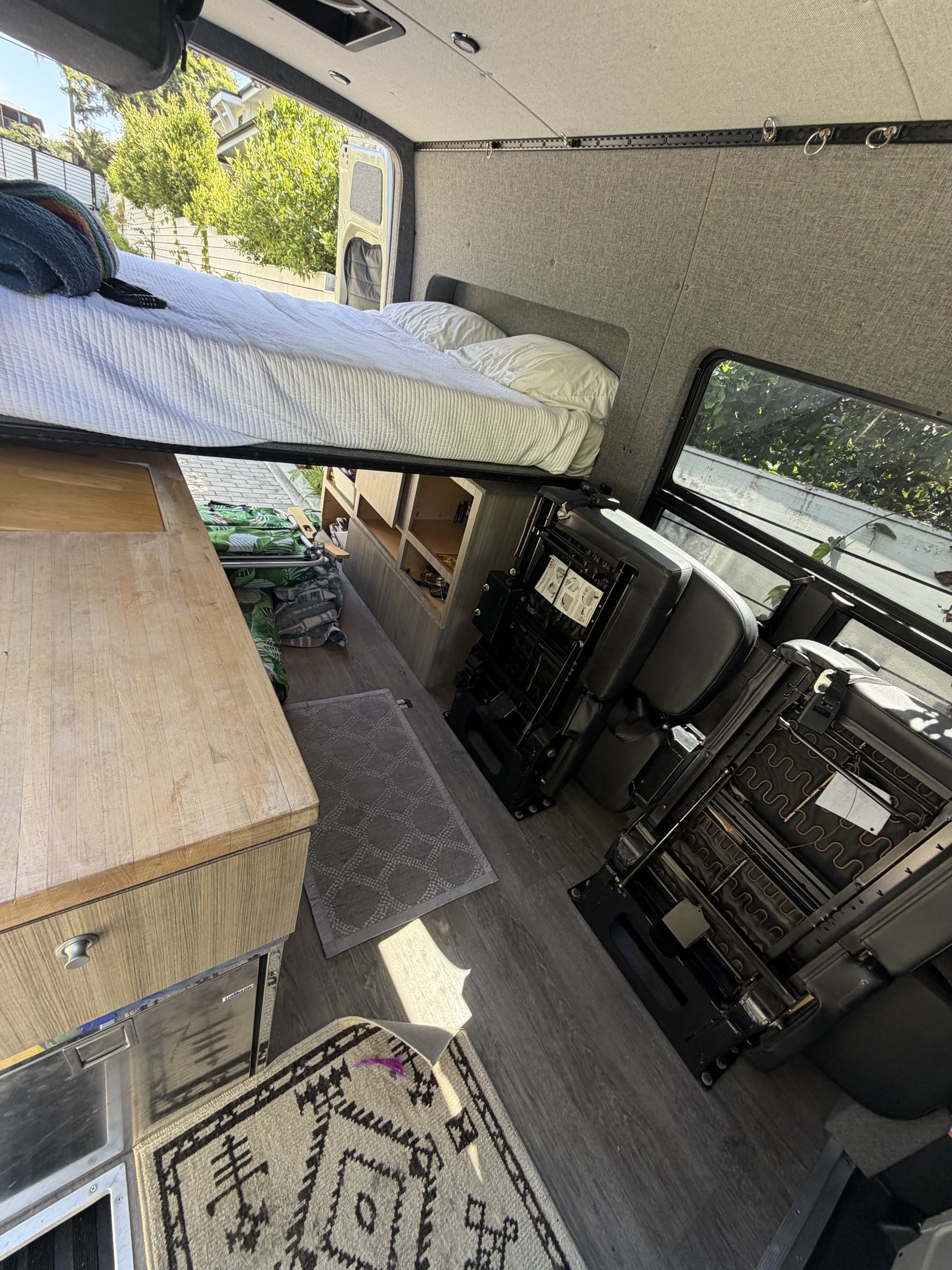 Sprinter camper interior showing raised bed, galley and passenger seating